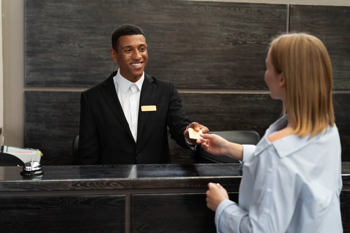 Un réceptionniste remet une carte de chambre à une cliente à la réception de l’hôtel